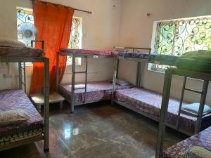 阿姆波尔NamahStay Hostel, Cowork & Artist residency Arambol的带三张双层床和两扇窗户的房间