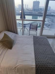 迪拜Studio in the heart of Sports City -great view & amenities!的一间卧室配有一张床铺和一张桌子,并设有一个阳台