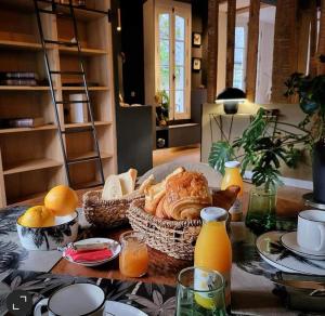 索姆河畔的圣瓦列里Maison d'hôtes du Jardin的桌子上放着一篮面包和橙汁