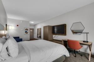 德斯坦德斯廷E购物中心区智选假日套房酒店的酒店客房配有一张床、一张书桌和一台电视。