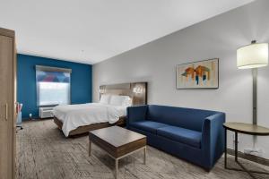 德斯坦德斯廷E购物中心区智选假日套房酒店的酒店客房,配有床和蓝色的沙发