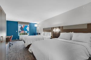 德斯坦德斯廷E购物中心区智选假日套房酒店的两张位于酒店客房的床,拥有蓝色的墙壁