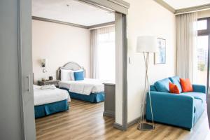 危地马拉桑坦德广场酒店的酒店客房,设有两张床和一张蓝色的沙发