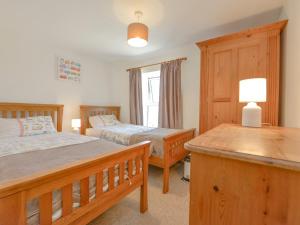 韦德布里奇Primrose Cottage的一间卧室配有两张床和一张带台灯的桌子
