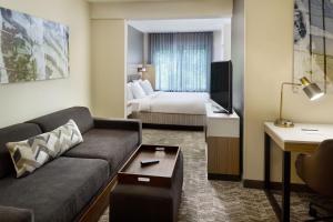 夏洛特斯普里赫尔套房酒店－夏洛特大学研究园的酒店客房设有一张沙发和一张床