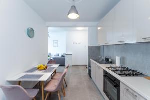 奥西耶克Sunrise & Sunset Apartmani - Self Check In的厨房配有白色橱柜和桌椅