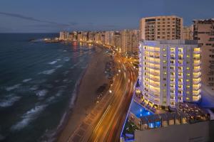 亚历山大Hilton Alexandria Corniche Hotel的享有海滩的夜间美景,设有建筑
