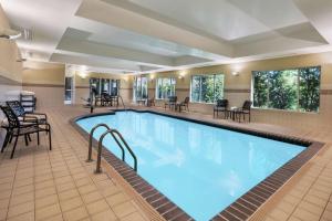 布莱克斯堡Hilton Garden Inn Blacksburg University的游泳池位于酒店客房内,配有桌椅