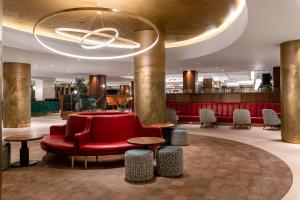 比肯希尔希尔顿伯明翰大都会酒店的大堂设有红色的沙发、桌子和吊灯