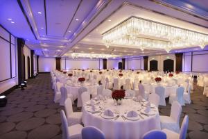 鲁瓦西昂法兰西希尔顿巴黎戴高乐机场酒店的宴会厅配有白色的桌椅和吊灯