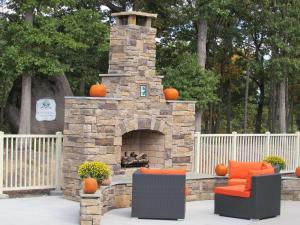 康科德Embassy Suites by Hilton Charlotte Concord Golf Resort & Spa的石头壁炉,配有橙色椅子和南瓜