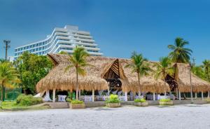 卡塔赫纳卡塔赫纳希尔顿酒店的棕榈树和草屋顶的度假村