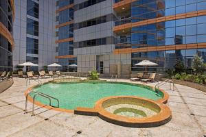 迪拜DoubleTree by Hilton Hotel and Residences Dubai – Al Barsha的一座高楼前的游泳池