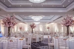 都柏林都柏林康拉德酒店的宴会厅配有白色的桌椅和粉红色的鲜花