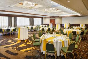 格林斯伯勒Embassy Suites by Hilton Greensboro Airport的宴会厅配有桌椅,提供黄色和白色的桌布
