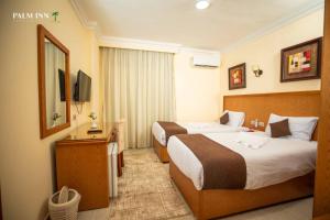 赫尔格达Palm Inn Suites Hotel的酒店客房设有两张床和电视。