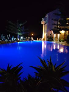 圣斯特凡诺迪卡马斯特拉Hotel La Playa Blanca的一座蓝色的泳池,晚上有一座建筑