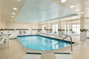 谢尔顿谢尔顿希尔顿花园旅馆的医院里的一个大型游泳池,配有桌椅