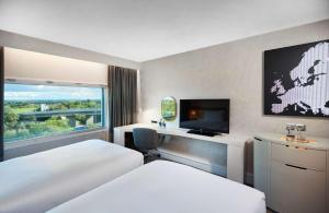 希灵登Hilton London Heathrow Airport的酒店客房设有两张床和一台平面电视。