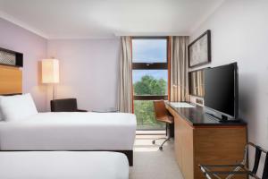 伦敦希尔顿伦敦肯辛顿酒店的酒店客房配有一张床和一张书桌及一台电视