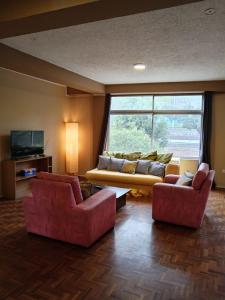 基多Tin House Quito的客厅配有2把红色椅子和1张沙发