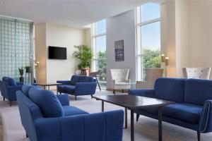 泰恩河畔纽卡斯尔希尔顿纽卡尔斯盖茨黑德酒店的一间设有蓝色椅子、桌子和窗户的等候室