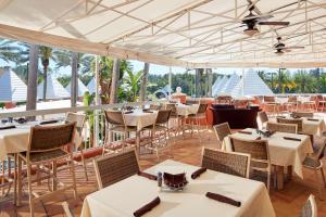 奥兰多Hilton Grand Vacations Club SeaWorld Orlando的餐厅设有白色的桌椅和天花板。