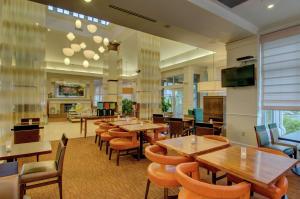 诺沃克诺沃克希尔顿花园酒店的餐厅设有桌椅和平面电视。