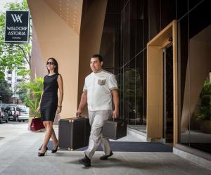 巴拿马城巴拿马华尔道夫阿斯托里亚酒店的带着手提箱走在街上的男人和女人