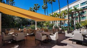 圣地亚哥DoubleTree by Hilton San Diego Del Mar的一间带桌椅和黄色遮阳伞的餐厅