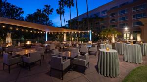 圣地亚哥DoubleTree by Hilton San Diego Del Mar的一间设有白色桌椅的餐厅,以及一座建筑