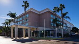 圣地亚哥DoubleTree by Hilton San Diego Del Mar的一座棕色的建筑,前面有棕榈树