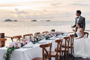 塔林甘海滩Conrad Koh Samui的站在海滩上婚礼桌旁的新娘和新郎