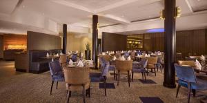 沃金沃金希尔顿逸林酒店的一间配备有桌子和蓝色椅子的用餐室