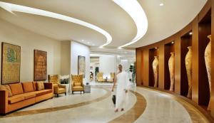 麦加Conrad Makkah的走在酒店大堂走廊的男人