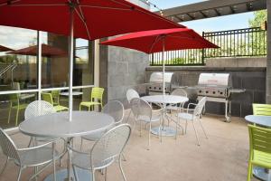 罗斯维尔Home2 Suites by Hilton Roseville Minneapolis的一个带桌椅和红色遮阳伞的庭院