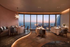 厦门Conrad Xiamen-Free Mini Bar的餐厅设有桌椅和大窗户。