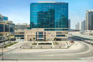 迪拜迪拜希尔顿逸林酒店 - 商务湾的前面有一条路的玻璃大建筑