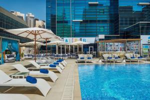 迪拜迪拜希尔顿逸林酒店 - 商务湾的大楼内一个带椅子和遮阳伞的游泳池