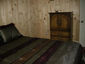 泰道沙克诺伊赛提尔度假屋的一间卧室配有一张床和一个木制橱柜