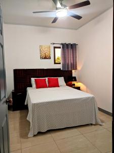 埃斯特利Este Hotel的一间卧室配有一张带红色枕头的床和吊扇