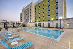 普莱诺Home2 Suites By Hilton Plano Richardson的酒店游泳池设有躺椅,酒店大楼