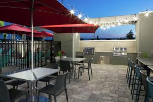 奥兰多Home2 Suites By Hilton Orlando Airport的一间带桌椅和红伞的餐厅