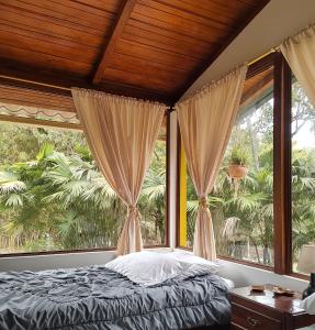 明多Senz Chalet Riverside - Mindo的一间卧室设有一张床和一个大窗户