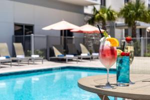 德斯坦Hilton Garden Inn Destin Miramar Beach, Fl的在游泳池旁的桌子上喝一杯