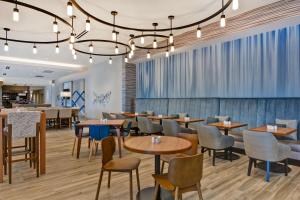 德斯坦Hilton Garden Inn Destin Miramar Beach, Fl的一间带桌椅和吊灯的餐厅