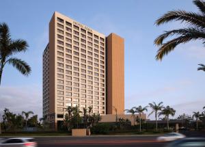 安纳海姆Hotel Fera Anaheim, a DoubleTree by Hilton Hotel的一座高大的建筑,前面有棕榈树