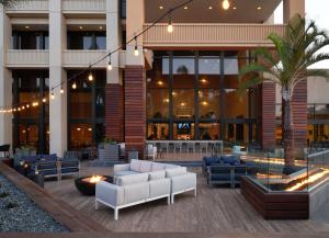 安纳海姆Hotel Fera Anaheim, a DoubleTree by Hilton Hotel的大厅,带有长沙发和棕榈树的建筑