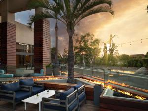 安纳海姆Hotel Fera Anaheim, a DoubleTree by Hilton Hotel的餐厅设有游泳池,并种植了棕榈树和灯