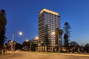珀斯Doubletree By Hilton Perth Waterfront的夜幕降临的城市街道上一座高楼